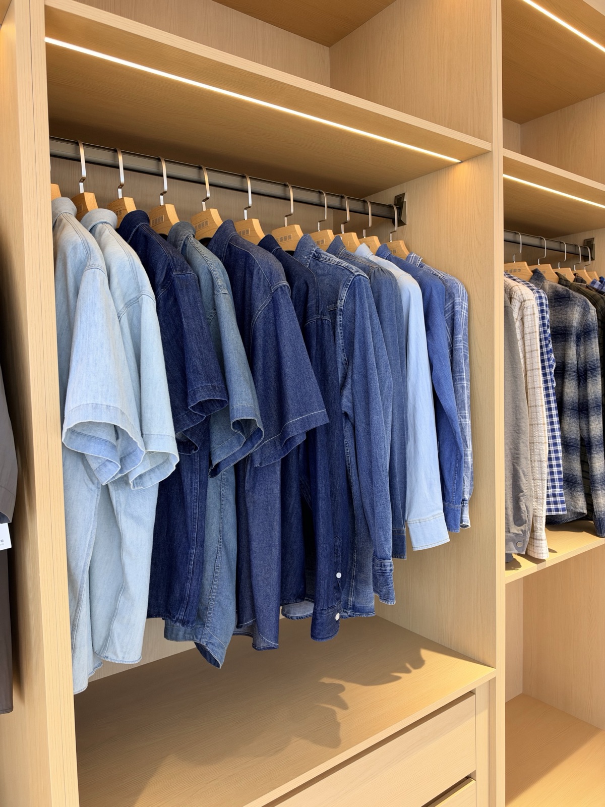 Denim shirt samples in light and dark blue displayed in a wooden cabinet